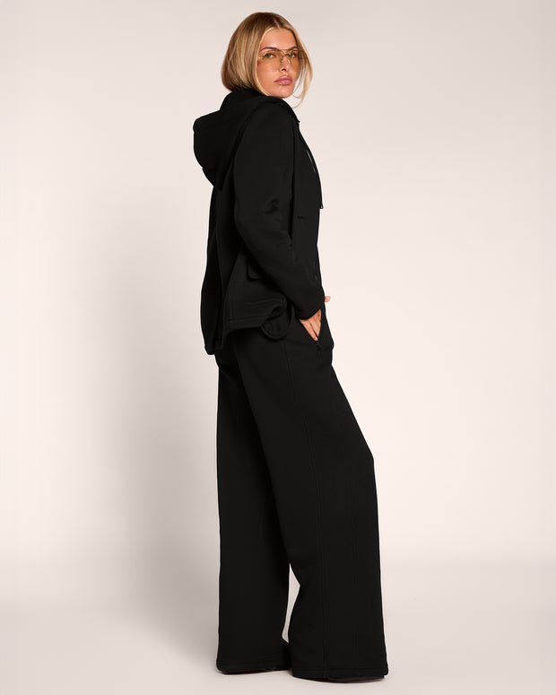 Full body side view of model wearing Fleecey Wide Leg Pull On Pant - Black paired with the Swuity Convertible Jacket - Black