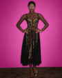 Model posing in Bombshell Midi Dress - Lace Black/Tawny in front of pink background