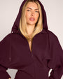 Close up of model in Croissant Fleecey - Garnet wearing hood up
